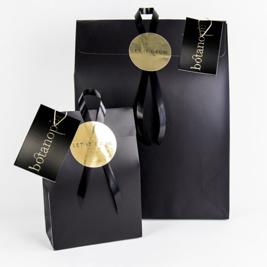 Product foto van gepersonaliseerde geschenkverpakkingen inclusief cadeaukaartje van Botanopia.  In elegant zwart en goud